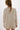 Person wearing a beige cable knit cardigan on a white background