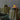 Two ghost-shaped candles with a lit candle in the foreground on a dark surface.