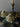 Two ghost-shaped candles on a table with a candlestick in the background.