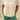 Person wearing a white t-shirt and green pants standing on sandy ground