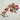 Handmade wool and cotton garland with pom poms and metal bells against a neutral textured background. 
