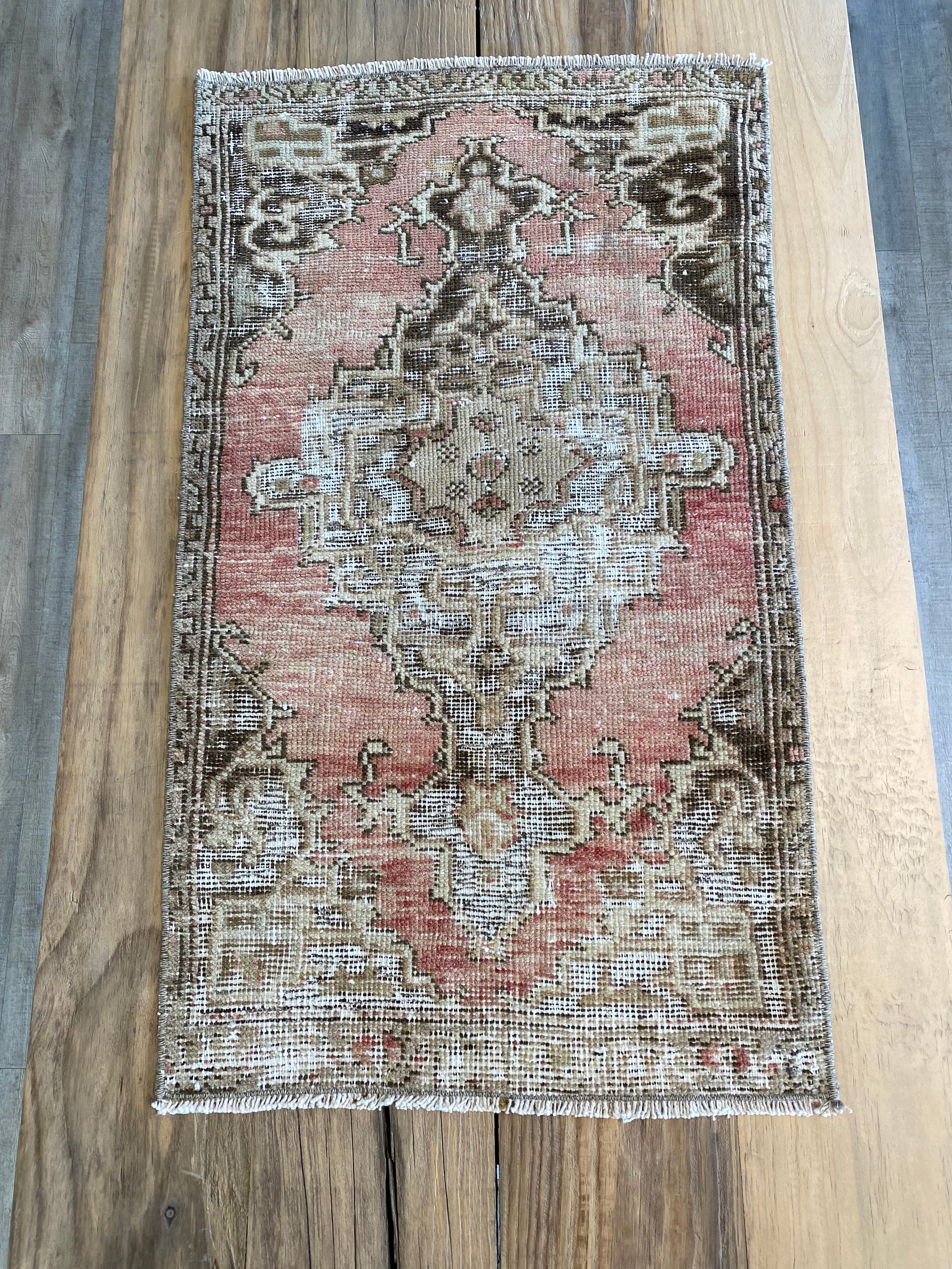 Dark and pale pink with beige, dark brown are the colours of this distressed Turkish rug. 