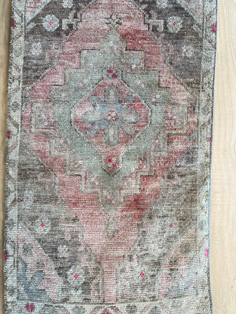 Turkish area rug in pale green with rose and pale pink, brown and pops of hot pink.