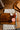 Wooden cutting board with a knife, small containers of jam, and a checkered cloth on a wooden surface.