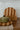 Green ceramic dish with a wooden lid on a wooden surface with a tiled wall background