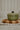 Green ceramic pot with a black handle on a wooden cutting board.