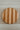 Round wooden cutting board with striped pattern on a checkered tablecloth