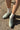 Light green shoes with white laces worn on a pavement.
