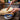Person spreading something on a slice of bread with a wooden spreader on a wooden cutting board.