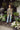 Woman standing outdoors with potted plants and a building in the background