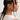 Side profile of a person with braided hair wearing a gold earring on a plain background.