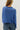 Person wearing a blue knitted sweater against a plain background
