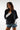 Woman wearing a black oversized sweatshirt and denim shorts on a white background