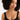 Woman wearing a black sleeveless top and pearl necklace on a white background