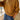 A person wearing a mustard yellow ribbed knit sweater and blue jeans, standing indoors near a window.