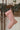 Red and white striped Christmas stocking hanging on a wooden mantel with greenery.