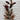 Artificial plant with brown leaves against a light gray brick wall