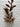 Artificial plant with brown leaves against a light gray brick wall