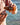 Person holding a bottle of hot sauce over an oyster by the water