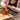 Person spreading jam on a cracker with a jar of Spicy Tomato Jam on a wooden board.