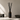 A reed diffuser bottle made of dark amber glass with a black label reading 'SANTAL N°33' with black reed sticks inserted, set on a tabletop against a warm beige wall with soft window light and shadows.