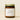 Candle jar with a minimal label that reads the scent name Santorini on a beige background.