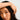 Close-up of a person with one hand touching their hair against a neutral background