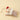 Decorative mouse with a red bow and striped pillow on a beige background