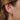 Gold earring worn by a person with brown hair.