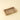 A rectangular stone tray with a natural travertine or marble texture in beige, brown, and cream tones, set against a solid light beige background.