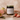 A candle with a label that reads strawberry, surrounded by fresh strawberries, passionfruit, and guava.