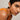Close-up of a person wearing an orange top against a neutral background