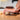 Person crushing garlic using the sauté spatula on a wooden block with a blurred kitchen background