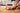 Person crushing garlic using the sauté spatula on a wooden block with a blurred kitchen background