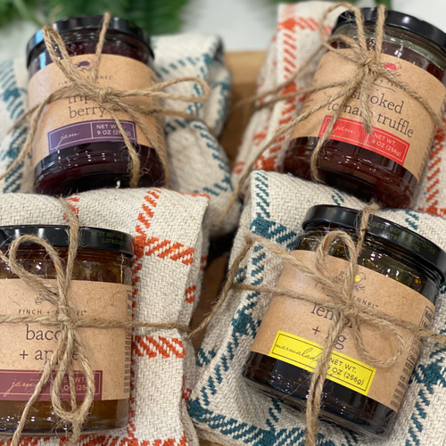 Beautifully packaged jam and marmalades ontop of colourful plaid tea towels, wrapped with jute twine. 