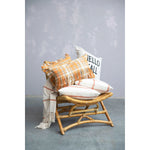 Plaid throw pillows on top of a wicker bench.