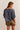 Woman wearing a blue oversized shirt and brown shorts on a beige background