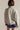 Person wearing a gray jacket with a logo on the back against a plain background
