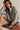 Woman wearing a gray oversized hoodie sitting on the floor against a plain background