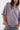 Person wearing a loose-fitting purple shirt and jeans on a white background