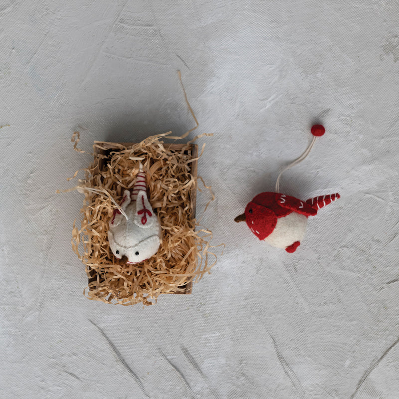 Felted wool bird ornaments with embroidery in a paper nest.  