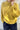 Person wearing a yellow knitted sweater against a light background