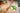 Person preparing a salad on a wooden cutting board with a knife