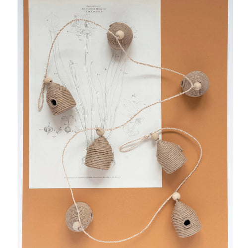 Handmade paper mache jute wrapped behive garland with wood beads displayed on top of a plant diagram.