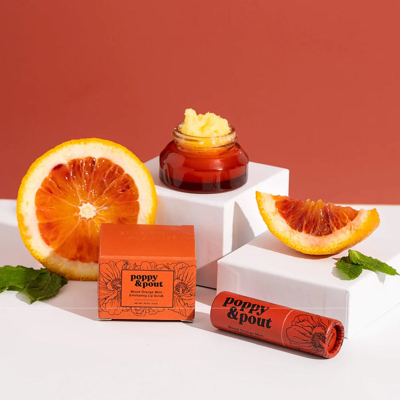 Blood orange slices and mint leaves with Poppy & Pout lip care products. 