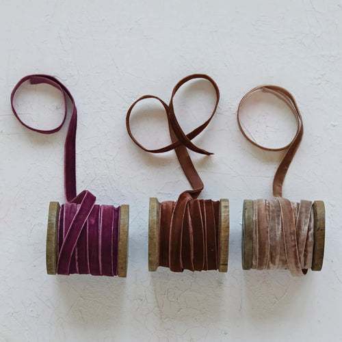 Velvet ribbons unraveled on a textured surface. 