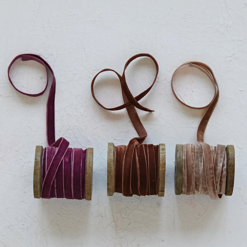 Velvet ribbons unraveled on a textured surface. 