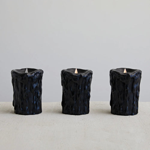 3 flameless black wax LED candles burning in a row.