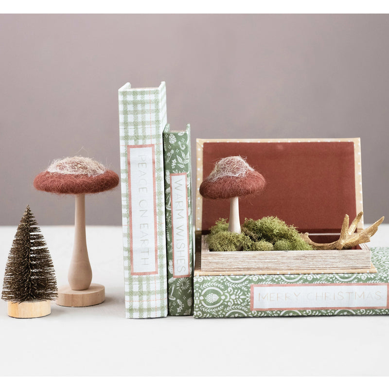 Canvas book storage boxes with subtle holiday wishes along the spine, styled with hand crafted mushrooms.