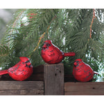 Three Cardinals on wooden post sitting infront of a Christmas tree.